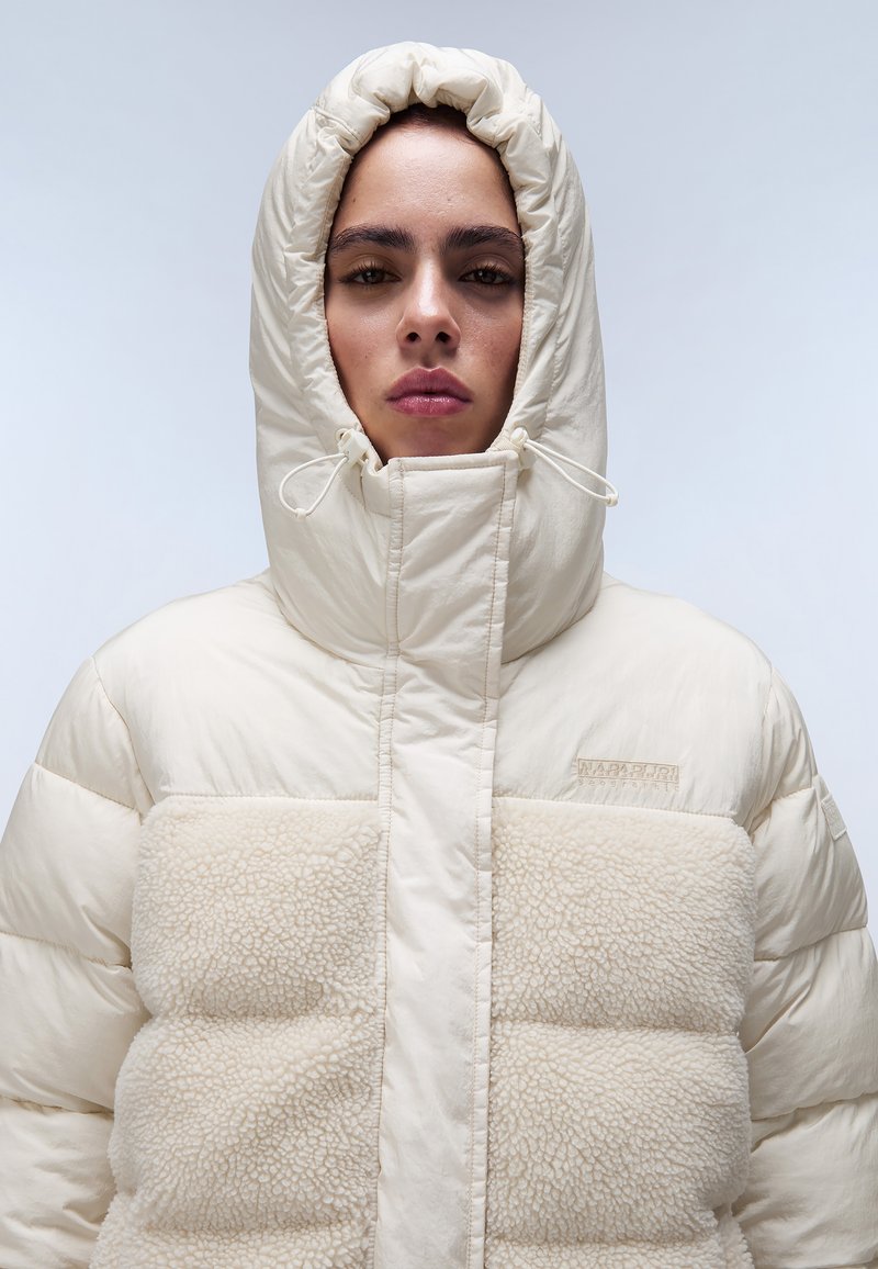 Giacca di puffer con un pannello frontale in fleece texturizzato e cappuccio. Caratterizzata da una chiusura con zip e cordoncini regolabili sul cappuccio.