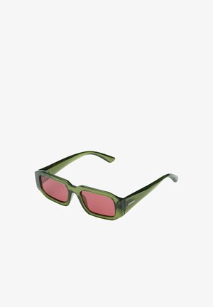 Lunettes de soleil rectangulaires vertes avec des montures épaisses et des verres teintés roses, inclinées pour montrer l'avant et le côté avec le logo Komono sur la branche.