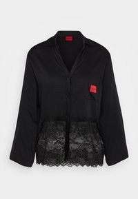 Black button-up shirt with a lace hem. Features a chest pocket with a red label. Made of smooth fabric with long sleeves and a collared neck.