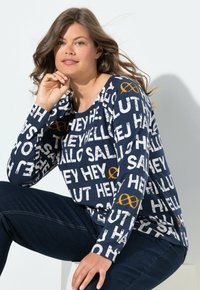 Dlouhý rukáv, modré tričko s kombinací velkého bílého a oranžového písma, kulatý výstřih a volný střih. Měkká bavlněná tkanina.