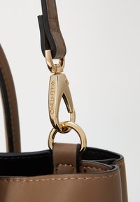 Borsa a tracolla in pelle marrone con hardware in oro, dotata di un'evidente chiusura a clip e fodera nera a contrasto. Texture liscia e cuciture precise.