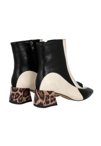 Botines de cuero negros y beige hasta el tobillo con punta afilada y tacones de bloque con print animal. Presentan costuras en zigzag a lo largo de la costura superior.