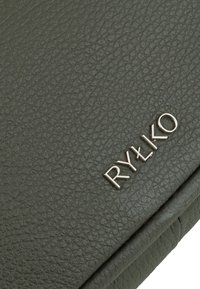 Tekstureret, mørkegrøn læderoverflade med et sølvfarvet "RYŁKO"-logo. Materialet ser fleksibelt ud med et subtilt kornmønster.