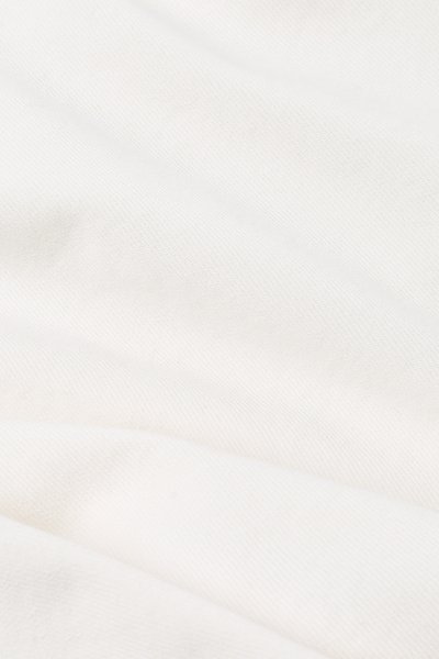 Zachte, licht gekreukte witte stof met een subtiele diagonale weefstructuur, gelijkmatig verlicht.