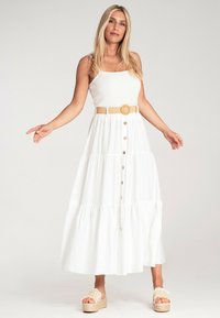Biała maxi sukienka z warstwowym fasonem, kwadratowym dekoltem i guzikami. Połączona z brązowym w plecionym pasku i beżowymi platformami.