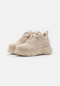 Beige sportskor med ovandel i slätt läder, rund tå, vadderad krage och tjock, texturerad sula. Har ton-i-ton snörning och varumärkesdetaljer.