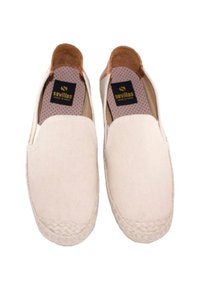 Zapatos de lona beige tipo slip-on, con punta redonda, acentos de yute trenzado en la suela y un forro de lunares que presenta una etiqueta negra.