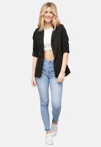 Must musternükk valge lühikese ülaosa peal, kerge siniste skinny teksade ja valgete tossudega. Tekstureeritud kangas ja kohandatud disain.
