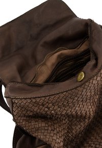 Brown leather bag with woven texture, interior pockets, light lining, and brass snap closure. Features a soft, flexible design.