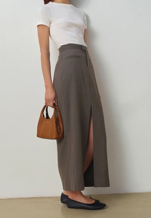 Sleeveless white shirt; long, grey skirt with a front slit; black flats; small brown bag with stitching details.