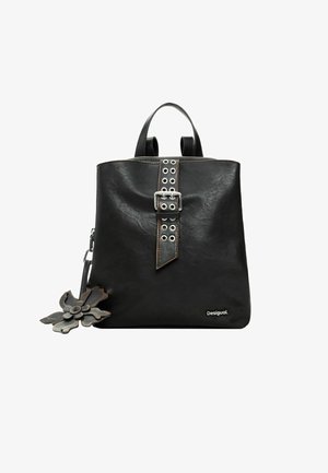 Čierna kožená taška typu tote s pevnou konštrukciou, vybavená stredovým popruhom s kovovými prackami a nitmi, s pripnutým kvetinovým ozdobným prvkom.