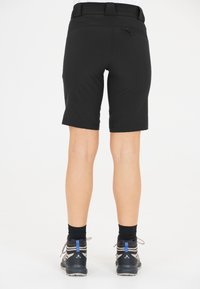 Svarta knälånga shorts med en slät yta, elastisk midja och en dragkedjeficka bak, kombinerat med grå och svarta vandringsskor.