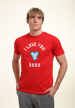 Czerwony bawełniany T-shirt z białym napisem "Kocham cię 3000" oraz niebieskim wzorem graficznym na środku. Krótkie rękawy i okrągły dekolt.