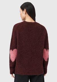 Burgundowa sweter dzianinowy o puszystej fakturze, z różowymi wzorami serc na rękawach i luźnym kroju.