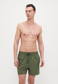 Grønne svømmehorts med elastisk talje og justerbar snor. Glat tekstur og design der går over knæet.