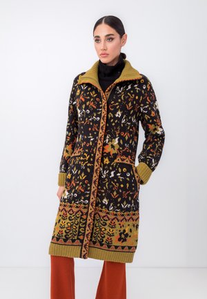 Knitted coat featuring a black base with floral patterns in shades of orange, yellow, and white; has a contrasting olive green collar and cuffs.