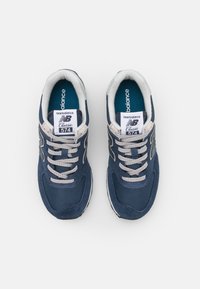 Tumesinine New Balance 574 tossud, mis on valmistatud võrkmaterjalist ja nahast, valged aktsendid, hallid paelad ja klassikaline brändimine keele peal.
