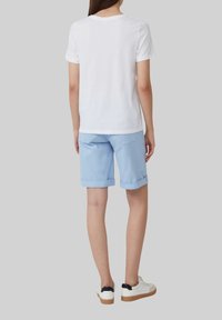 Witte korte mouwen t-shirt gecombineerd met lichtblauwe opgerolde shorts, met achterzakken en witte sneakers met zwarte accenten.