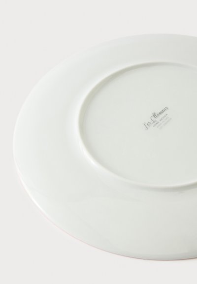 Assiette en céramique blanche vue de dos, avec une petite étiquette centrée indiquant le nom de la marque et les détails du design.