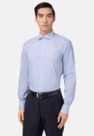 Camicia a righe blu chiaro con colletto a punta, maniche lunghe e chiusura con bottoni, abbinata a pantaloni blu navy e una cintura nera.