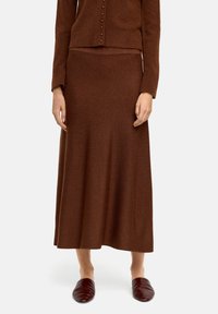 Brąska dziana długa spódnica wykonana z miękkiego materiału, z delikatną fakturą. Zestawiona z dopasowanym brązowym kardiganem i ciemnym obuwiem.