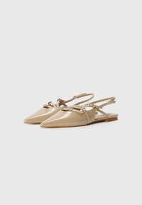 Beige patent leather slingback shoes with a pointed toe, adjustable straps, and silver hardware accents. Flat sole and minimalist design.