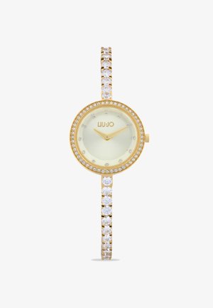 Gold-tone watch with a round face, greenish dial, and crystal accents on the bezel and strap. Features delicate arms and a minimalist style.