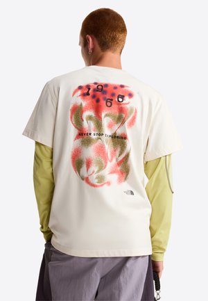 Helles cremefarbenes T-Shirt mit kurzen Ärmeln und einem bunten abstrakten Design auf der Rückseite, das den Text "1966" und "NEVER STOP EXPLORING" enthält.