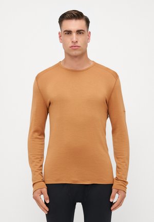 T-shirt à manches longues, col rond, de couleur caramel chaud. Fabriqué en tissu doux avec un design ajusté et des poignets côtelés. Texture lisse avec des coutures minimales.