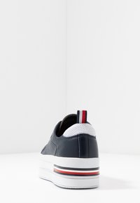 Baskets en cuir bleu marine avec un col en maille blanche, des accents texturés et une semelle plateforme blanche ornée de rayures rouges et bleues.