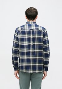 Marineblaues und grünes kariertes Flanellhemd mit langen Ärmeln, Button-Down-Kragen und Standard-Passform. Weiche Textur und sichtbares Rückenpasse-Detail.