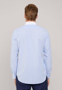 Camisa de botones de manga larga en azul claro con rayas verticales blancas, con un cuello blanco en contraste y un bajo redondeado, hecha de una tela suave.