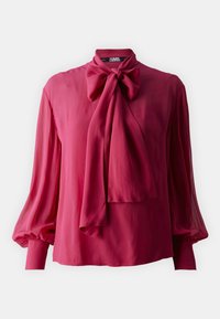 Slips bluse i rig magenta, lavet af letvægtigt stof. Har lange, puffede ærmer og en draperet sløjfedetalje ved halsudskæringen.