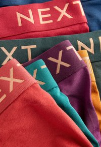 Stack di boxer colorati da uomo con elastici in vita che mostrano parzialmente il marchio "NEXT".