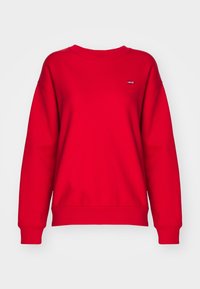 Sweat-shirt rouge à manches longues avec col ras du cou et petit patch logo Levi's sur le côté gauche de la poitrine, présenté sur un fond blanc uni.