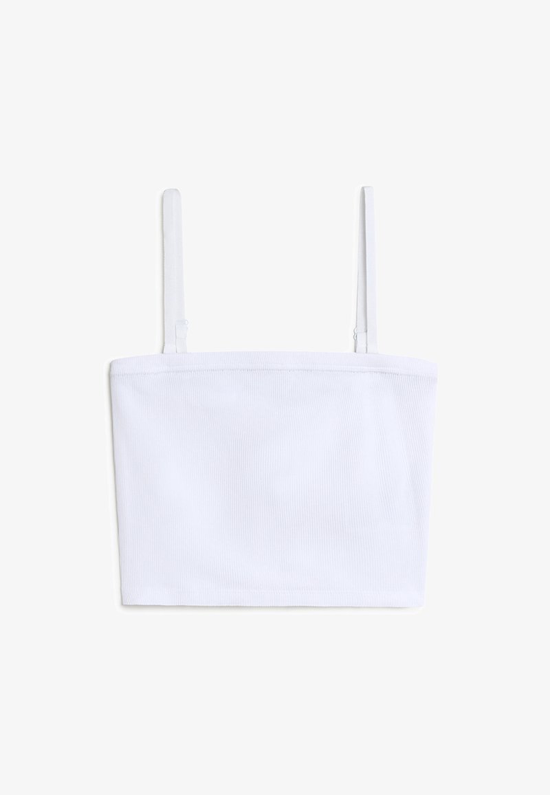 Crop top bianco a costine con sottili spalline regolabili e scollatura dritta. La texture del tessuto appare morbida e leggermente elasticizzata.