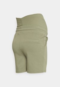 Calções verde em mistura de algodão com cintura elástica e um bolso nas costas. Apresentam um design de cintura alta e uma textura suave.