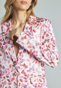 Blazer floreale bianco con motivi di foglie ad acquerello rosa e viola. Presenta rever a punta e due tasche frontali, realizzato in un tessuto leggero.