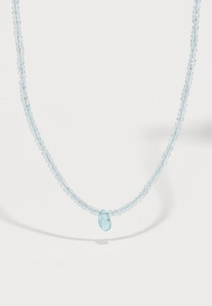 Collier délicat avec des perles facettées bleu clair et un pendentif en forme de goutte centrale, présenté sur un fond blanc uni.