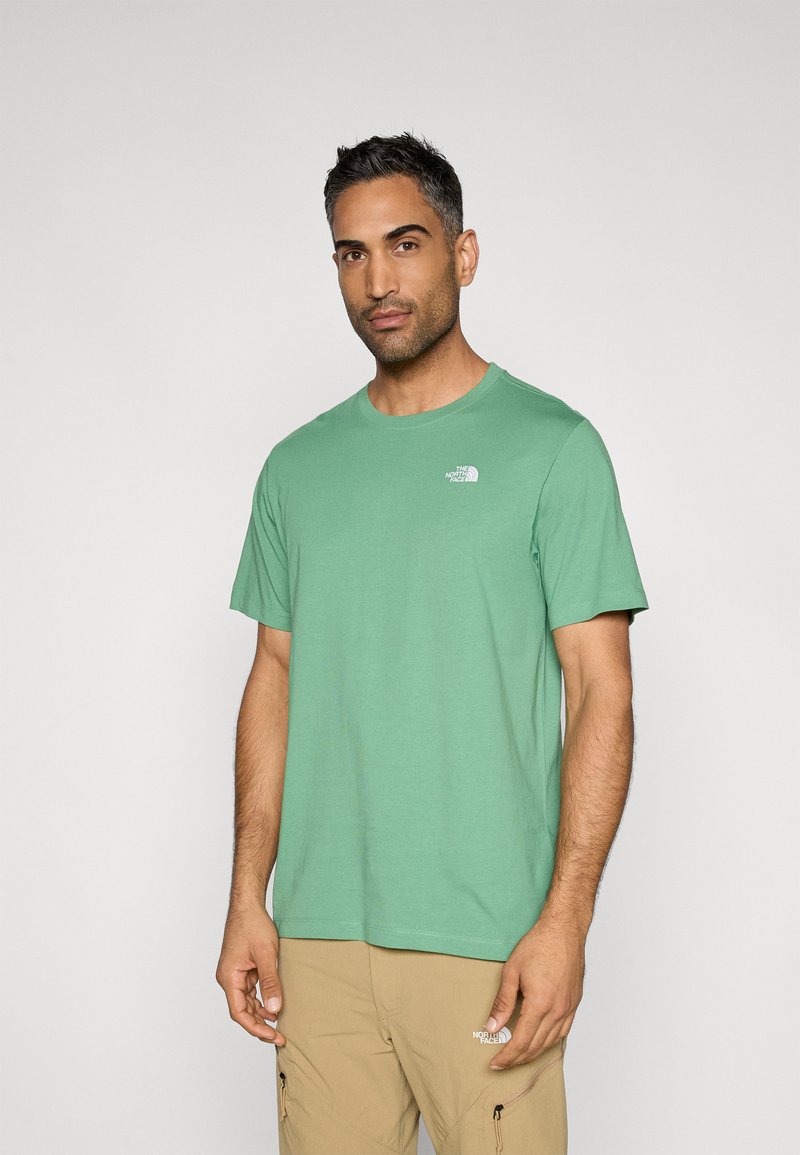 Πράσινο βαμβακερό t-shirt με λαιμόκοψη και κοντά μανίκια, με ένα μικρό λευκό λογότυπο στην αριστερή πλευρά του στήθους. Λεία υφή υφάσματος.