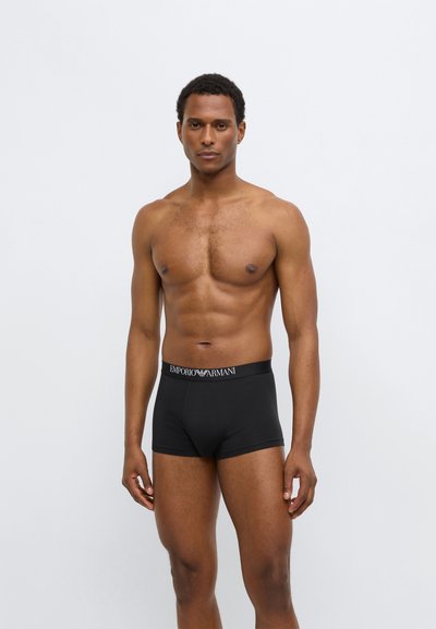 Juodi bokseriniai apatiniai su elastiniu juosmeniu, ant kurio yra „Emporio Armani“ logotipas. Minkšta, tampri medžiaga su glaudžiu dizainu.