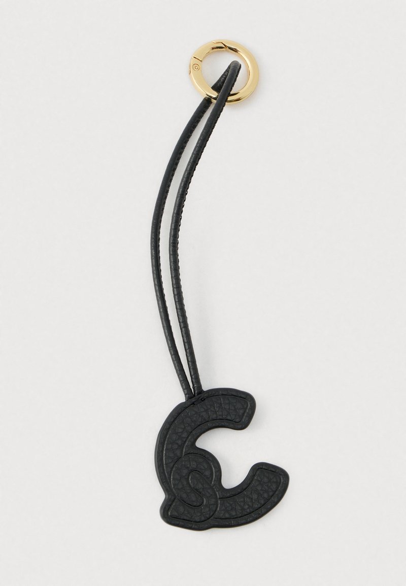 Černý texturovaný kožený přívěsek ve tvaru písmene "C" s dvojitým smyčkovým páskem a zlatým kovovým kroužkem na bílém pozadí.