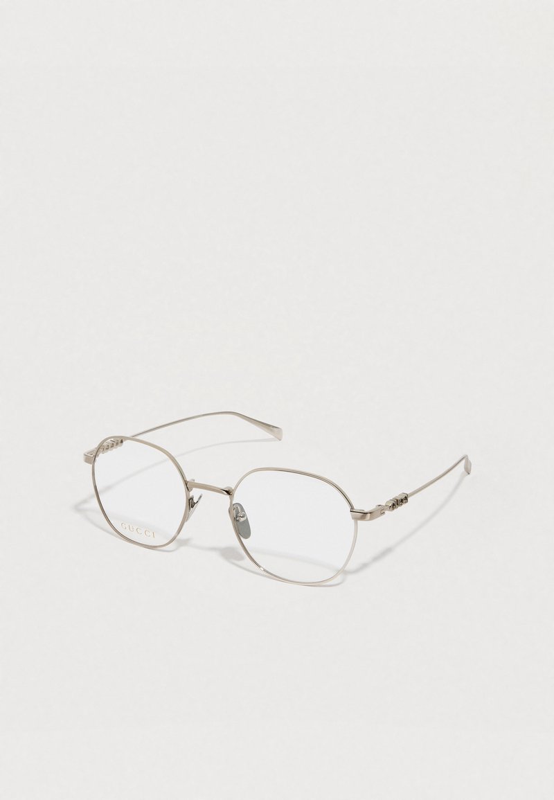 Óculos Gucci com armação de metal prateado; formato octogonal; lentes transparentes; detalhes decorativos nas hastes; plaquetas nasais ajustáveis.