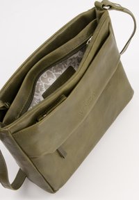 Olive green leather shoulder bag with a textured finish, featuring a zippered compartment and a patterned interior lining.