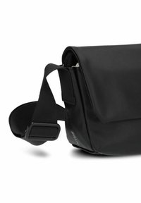 Borsa a tracolla nera realizzata in pelle liscia e opaca. Presenta una pattina pieghevole e una tracolla regolabile con una chiusura robusta. Design minimalista.