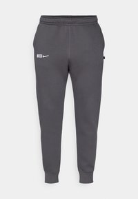 Sive Nike hlače za trening s slim fit krojem, ki imajo bel "INTE" logotip in elastičen pas. Gladka tekstura z rebrastimi manšetami.
