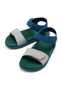 Calzado con un diseño bicolor que cuenta con una correa sintética gris y acentos azules, montado sobre una suela de goma verde texturizada.