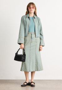 Lys blå denimjakke, matchende skjørt, teksturert akva strikket topp, svart mini bag, og svarte flate sko. Solbriller fullfører antrekket.