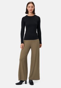 Černý dlouhý rukáv s kulatým výstřihem, zkombinovaný s khaki širokými ribbed kalhotami. Moderní design s hladkou texturou a přiléhavým siluetou.