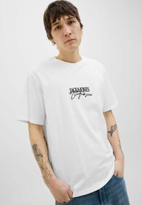Baltas medvilninis marškinėlis su juodu spaudiniu "JACK&JONES" ant krūtinės; trumpomis rankovėmis, laisva forma ir apykaklės dizainu.